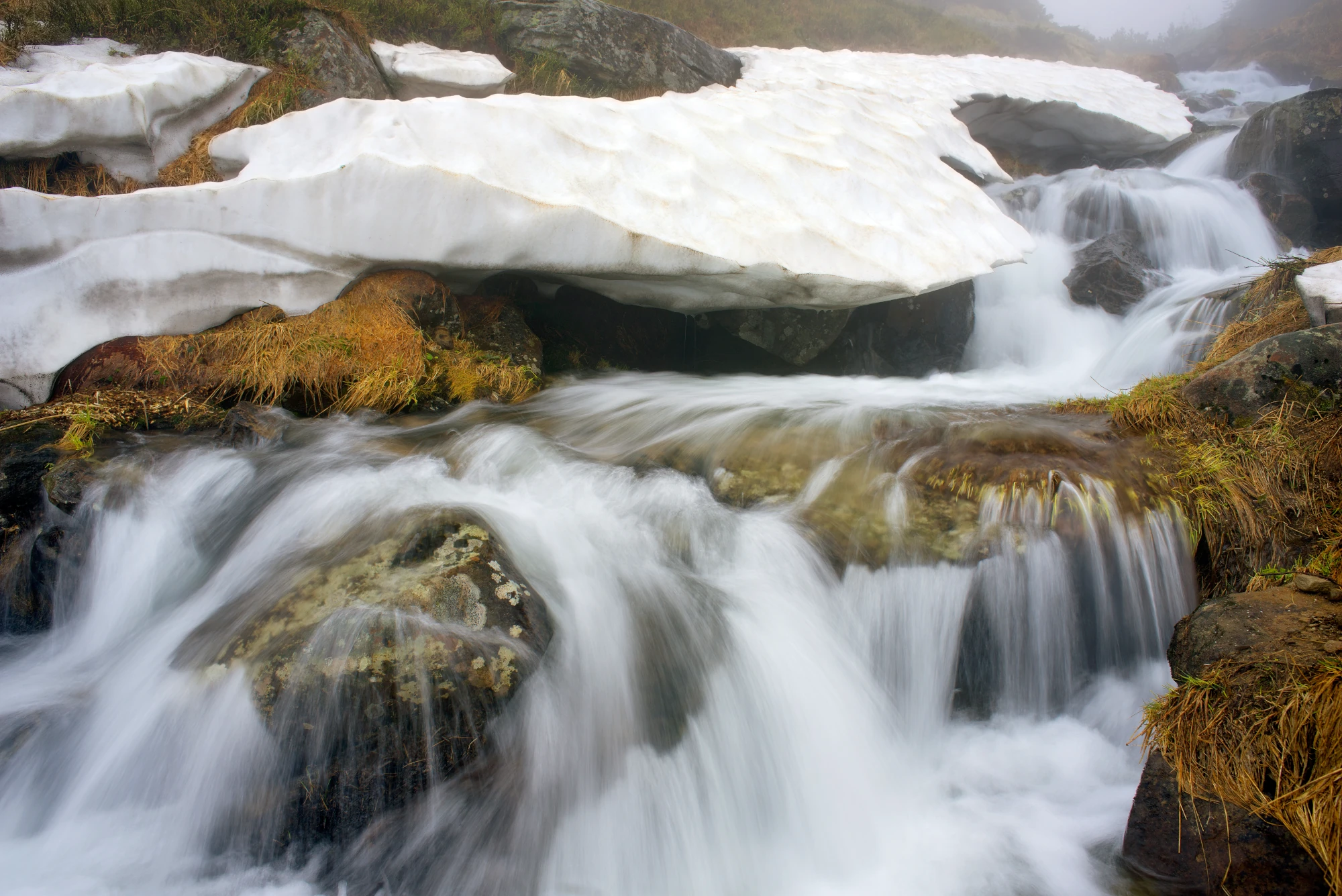 Das Bild zeigt einen reißenden Fluss, auf dem Teilweise noch Eis zu sehen ist. Das Bild ist ein Teil des Blogbeitrag über demineralisiertes Wasser.